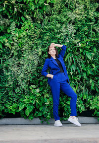Mid adult woman posing against plants