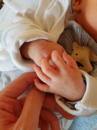 Cropped hand of parent holding baby hand