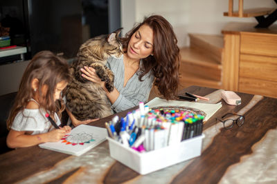 Mother and daughter drawing while sitting at home