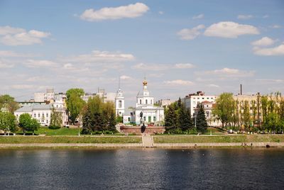 Buildings at waterfront against cloudy sky