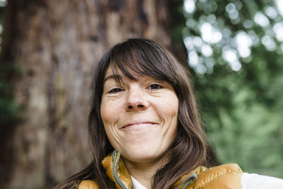 Woman smiling near large redwood tree