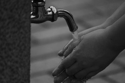 Cropped image of person washing hands in tap water