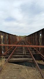 Abandoned railroad tracks against sky