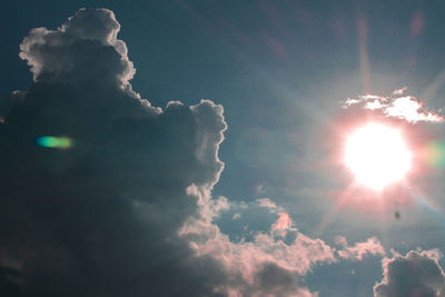 Low angle view of sunlight streaming through clouds