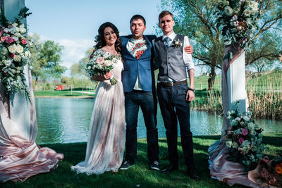 Portrait of happy friends standing against stone wall