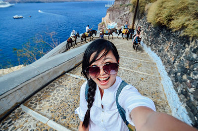 High angle portrait of smiling woman standing on steps against sea