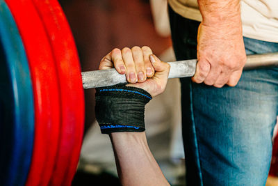 Midsection of man holding dumbbell