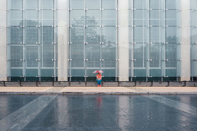 Rear view of man walking on glass building