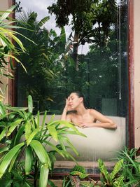 Low angle view of young woman sitting on window