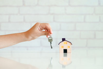 Close-up of hand holding bottle against wall