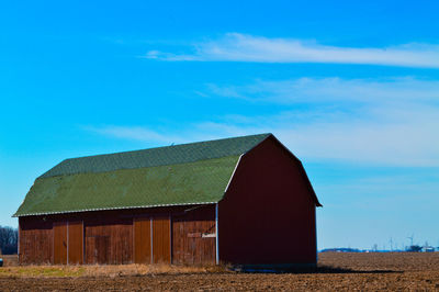 Barn on field against blue sky