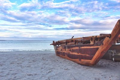 Boat moored on beach against sky