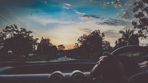Man seen through car windshield at sunset