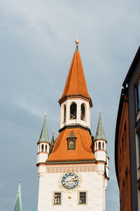 Low angle view of clock tower amidst buildings against sky