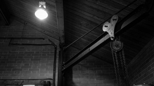 Low angle view of illuminated light bulb hanging on ceiling