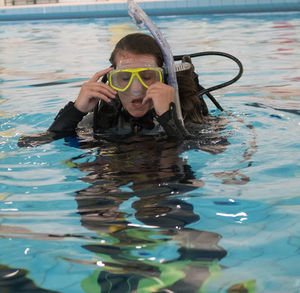 Happy woman with swimming goggles in pool