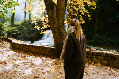 Rear view of woman standing by tree