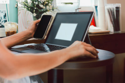 Midsection of woman using laptop at home
