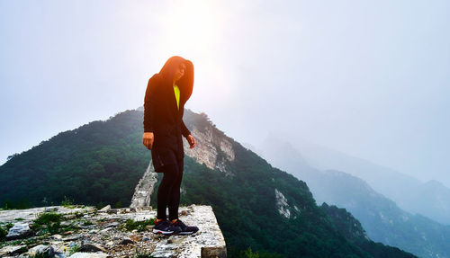 Low angle view of man standing on mountain against sky