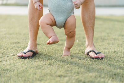 Low section of man with baby standing on grass