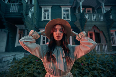 Portrait of young woman standing in front of building