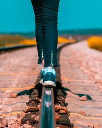 Low section of woman standing on railroad track