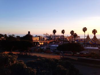 Silhouette trees and cityscape against clear sky during sunset