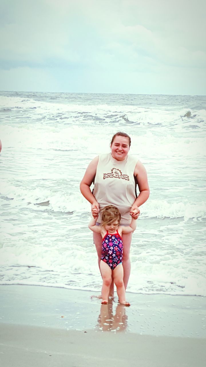 sea, beach, water, horizon over water, shore, sand, lifestyles, leisure activity, sky, full length, vacations, childhood, person, standing, casual clothing, rear view, wave, elementary age