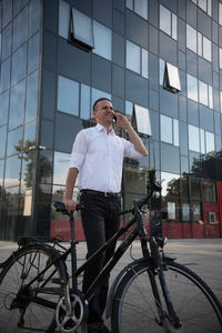 Full length of man standing by bicycle in city