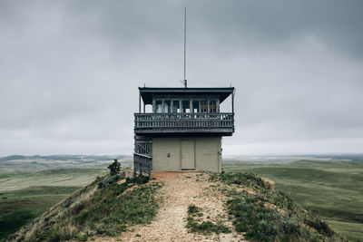 View of tower on landscape against cloudy sky