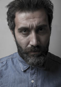 Close-up portrait of bearded man against wall