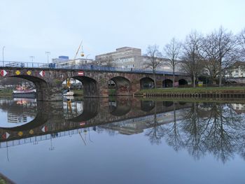 Arch bridge over river in city against sky