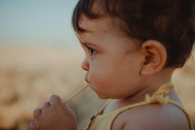 Close-up of baby girl eating candy outdoors