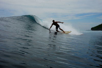 Man surfing in sea against sky