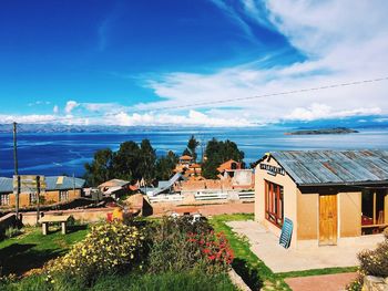 Houses by sea against blue sky