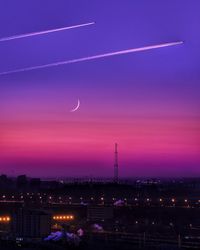 Illuminated cityscape against sky at sunset