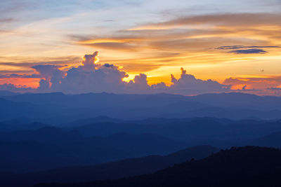 Scenic view of dramatic sky over silhouette mountains during sunset