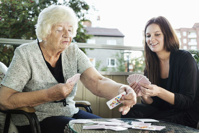 Grandmother and granddaughter playing cards on porch