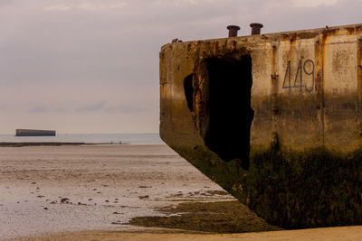 Old rusty metal on beach against sky
