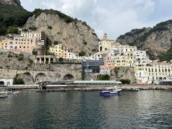 Buildings by river against mountain