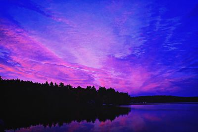 Reflection of silhouette trees in calm lake