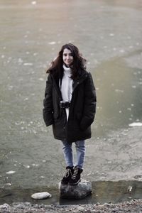 Full length portrait of happy woman standing in water