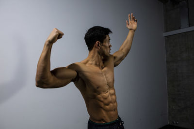 Shirtless muscular man standing against wall