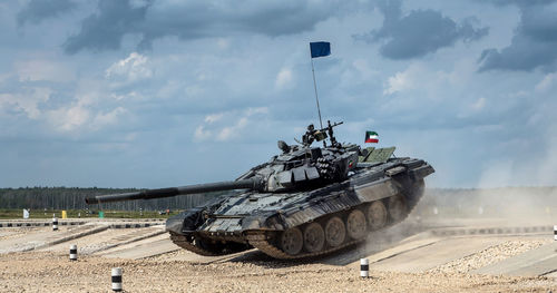 Tank moving at patriot park against cloudy sky