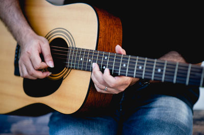 Midsection of man playing guitar while sitting outdoors