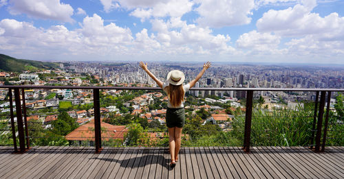 Tourist woman with raising arms from beautiful belvedere in belo horizonte, minas gerais, brazil