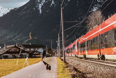 Multiple image of man by train on footpath against mountain