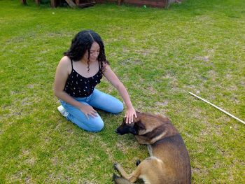 Teenage girl stroking dog on grass