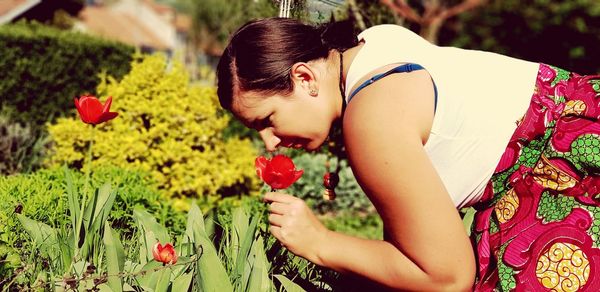 Midsection of young woman with red flowers