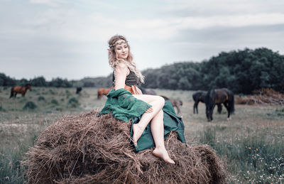 Full length of young woman sitting on field